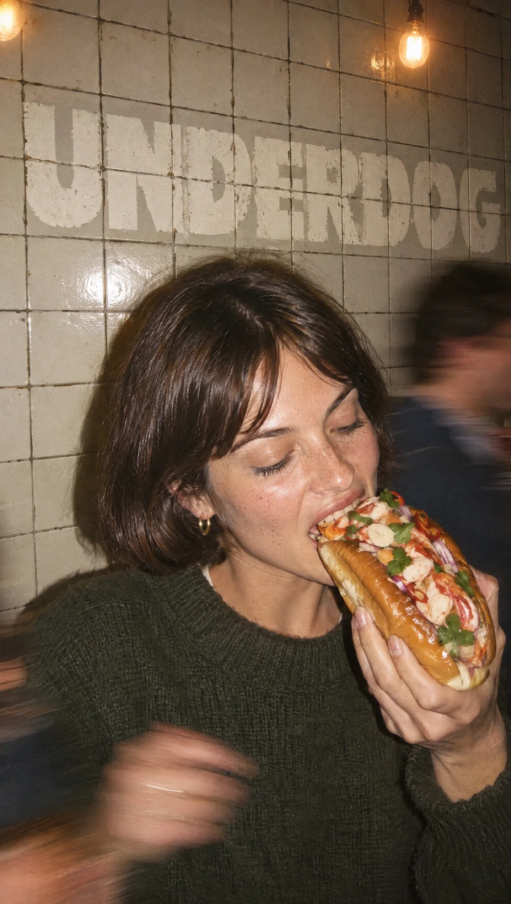 En gäst tar en tugga av en lobster roll hos Underdog